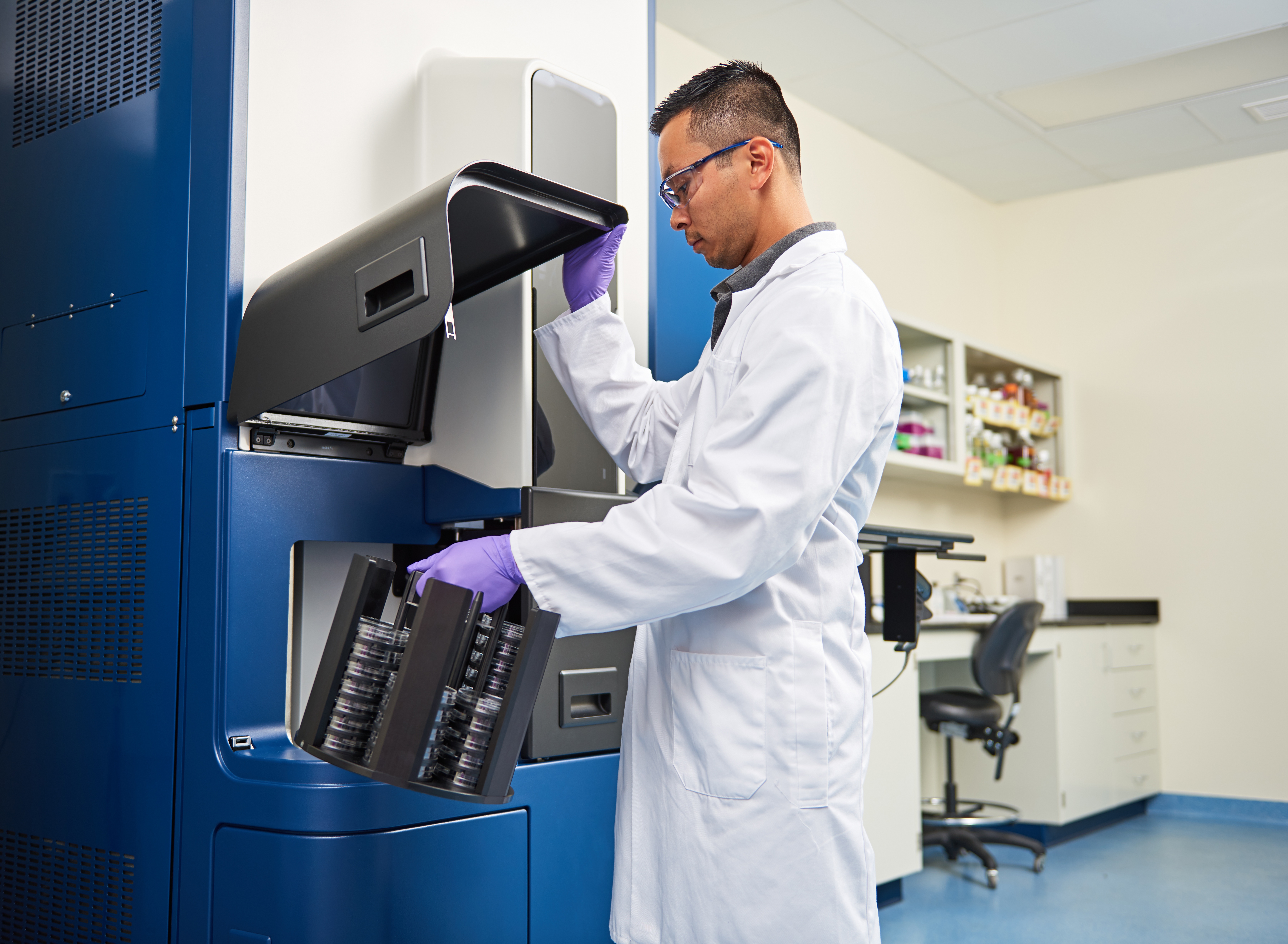 Pharmaceutical lab technician loading Growth Direct® System for automated QC microbiology testing.